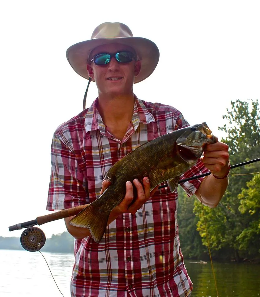 A smallmouth bass held above a river